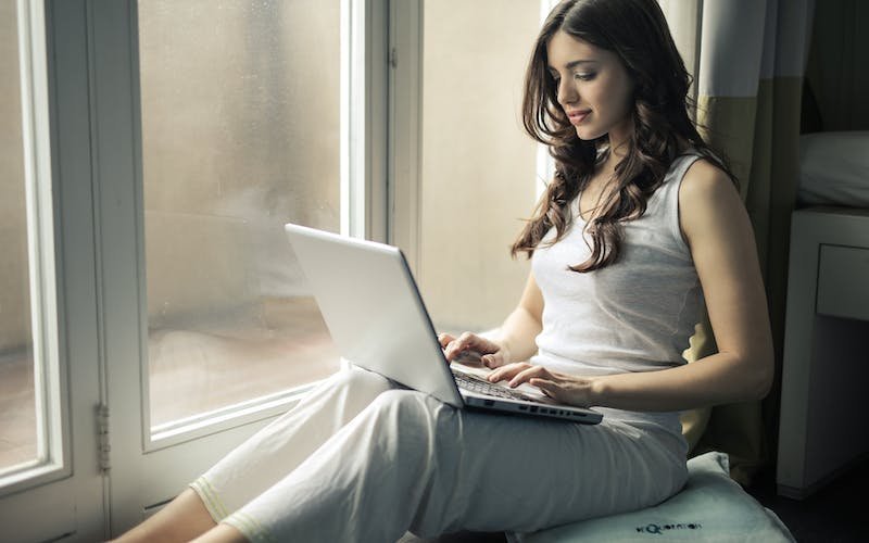 women sitting next to door while using laptop